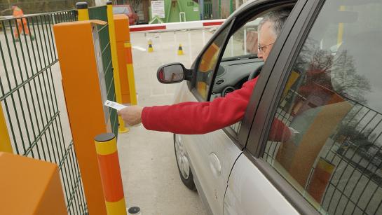 man zit in wagen en badget aan slagboom