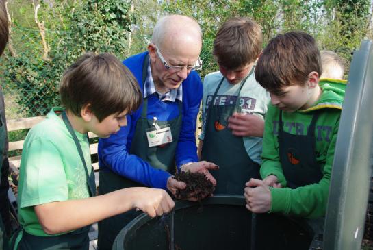Compostmeester bestudeert compostvat met scholieren