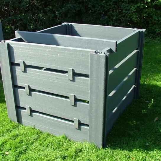 Een grijze kunststoffen compostbak in de tuin