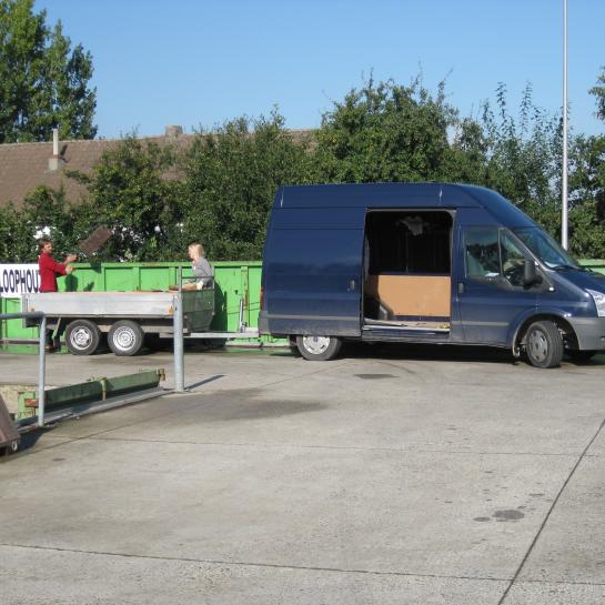 mensen laden bestelwagen uit op recyclagepark