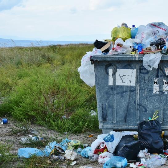 Een container puilt over van het afval in de natuur